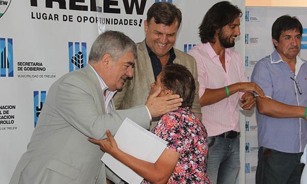 El exgobernador junto a Pérez Catán entregan el título a una vecina.