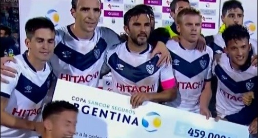 El capitán Cubero sostiene el cheque simbólico obtenido tras el triunfo de Vélez.