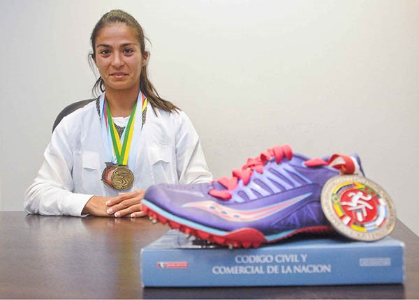 Una vida, dos pasiones. María Ayelén Diogo sentada, de cara a su futuro. Con el libro del Código Civil que será su herramienta de trabajo como abogada y las zapatillas de atleta.