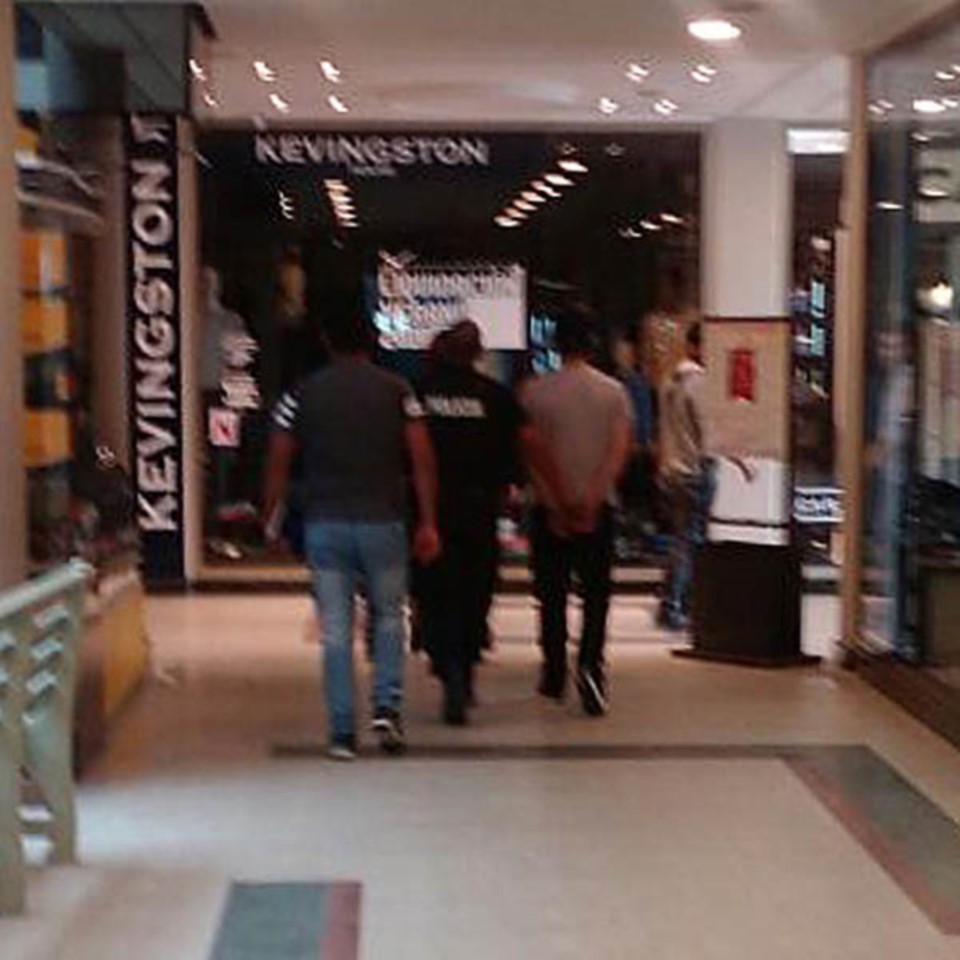 Uno de los delincuentes sale de un shopping apresado por la Policía.