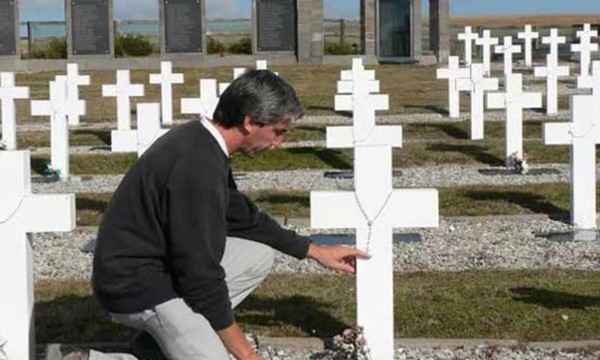 Julio Aro en Malvinas arrodillado ante las tumbas de ex compañeros.