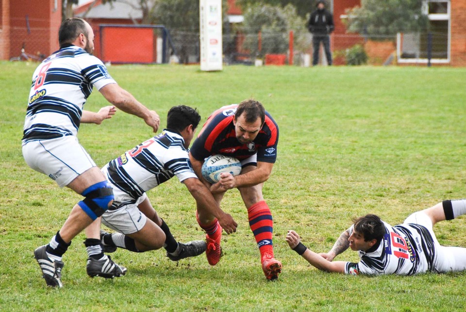 Braulio Bartolo, referente de Madryn, intenta avanzar ante la marca de tres jugadores.