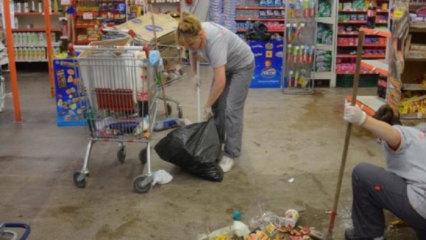 Empleadas del supermercado limpian los destrozos luego del saqueo relámpago.