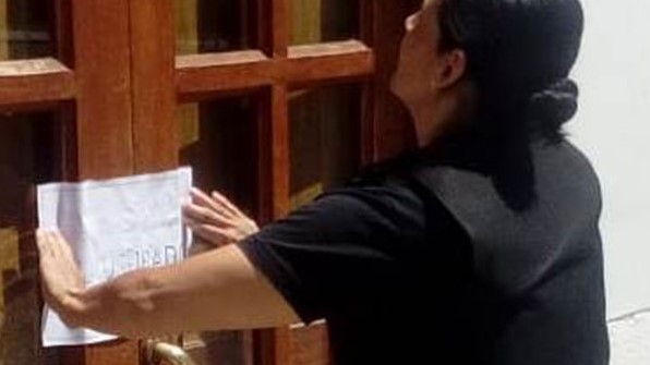 Una policía colocando la faja de clausura al histórico bar dolavense.