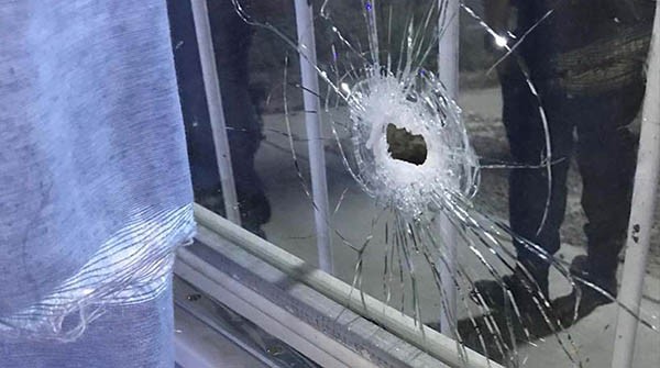 Uno de los cristales destrozados por los disparos en la subcomisaría.