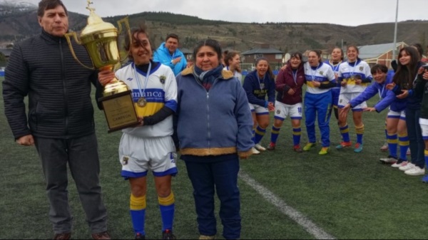 Fátima Gherbi posa con la copa junto a Víctor Tejada, presidente liguista, y junto a Ana Millalonco, referente del fútbol femenino cordillerano cuyo nombre nomina el torneo. Foto: Liga del Oeste.