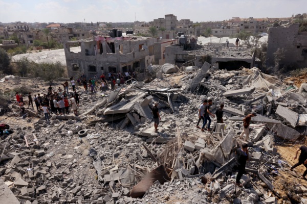 Palestinos buscan entre los escombros de los edificios destruidos tras un ataque israelí.