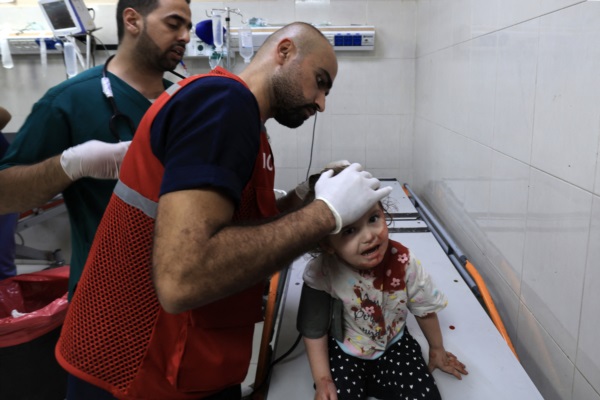 El enfermero palestino atiende a una niña con una herida a en la cabeza en el hospital Nasser.