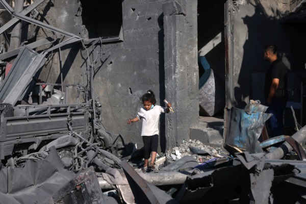 Una niña palestina camina sobre los escombros mientras otros inspeccionan los daños tras el bombardeo israelí en Rafah.