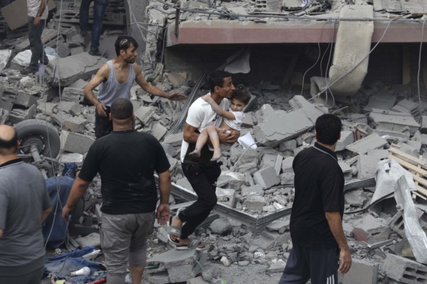 Un palestino lleva a un niño rescatado de una casa familiar, destruida en un ataque aéreo israelí sobre la ciudad de Gaza.