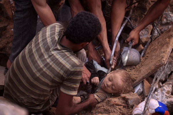 Palestinos desentierran el cadáver de un niño de entre los escombros de un edificio del campo de refugiados de Nuseirat.