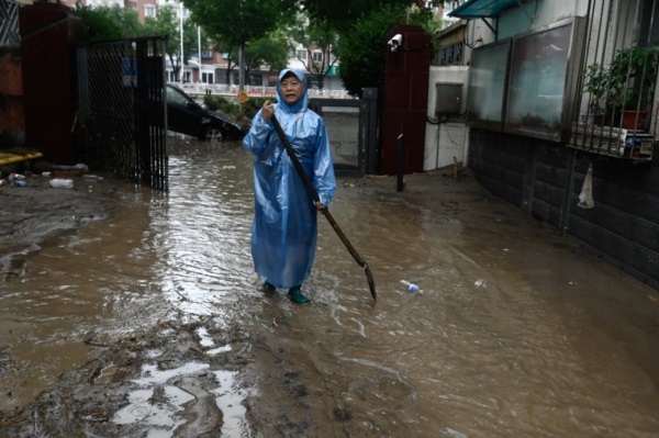 Un hombre camina por una calle inundada tras las fuertes lluvias caídas en el distrito de Mentougou, en Pekín.